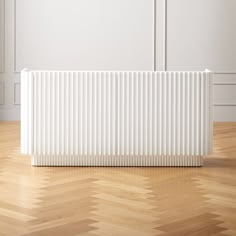 a white radiator sitting on top of a wooden floor next to a wall