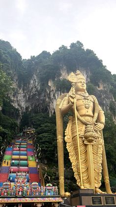 there is a giant statue in front of the mountain with many other statues on it