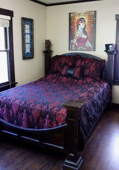 a bedroom with a large bed and wooden flooring next to two windows, framed pictures on the wall