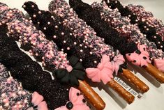 there are many donuts with pink and black icing on the top one is decorated