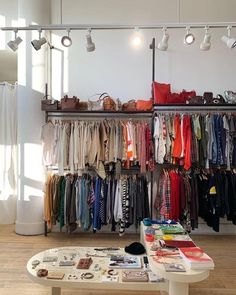 a room filled with lots of different types of clothes and bags on shelves next to a table