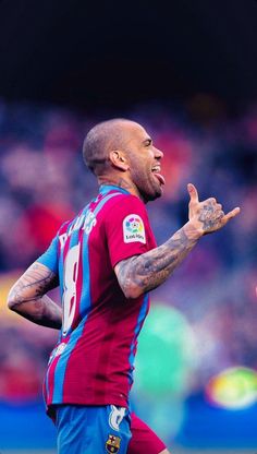 a man with tattoos on his arms and chest standing in front of a soccer ball