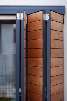 an open window with wooden slats on the outside and inside, in front of a white wall