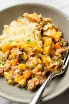 a bowl filled with mashed potatoes, meat and veggies next to a fork