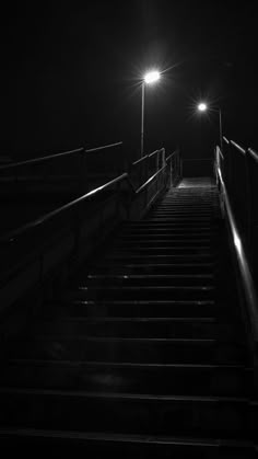 the stairs are lit up at night with street lights above them in black and white