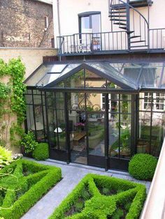 an enclosed patio with lots of green plants in the center and stairs leading up to it