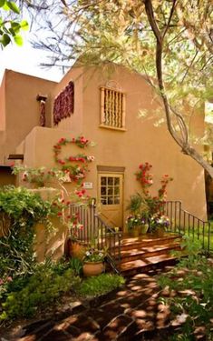 an adobe house with flowers on the windows and steps leading up to it's front door