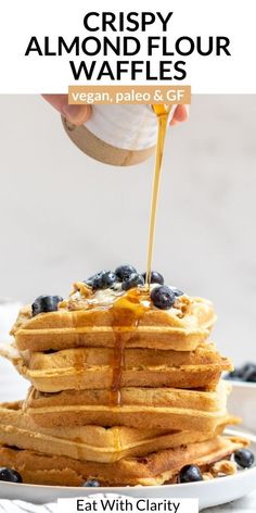 a stack of blueberry crispy almond flour waffles with syrup being drizzled on top