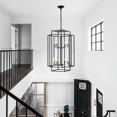 a chandelier hanging from the ceiling in a room with white walls and black railings