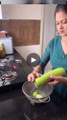 a woman is using a green knife to cut up an apple in a bowl on the kitchen counter