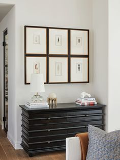 a living room with pictures on the wall and a black dresser in front of it