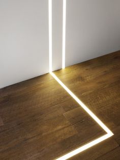 an empty room with two white lights on the floor and one light up in the air