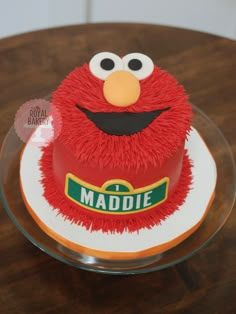 the cake is decorated with red frosting and has a sesame character on it