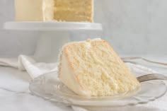 a slice of white cake on a glass plate with a fork next to the cake