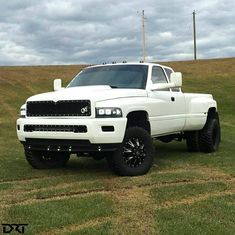 a white truck parked on top of a grass covered field