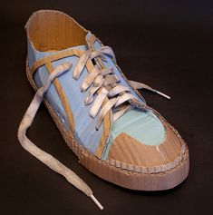 a pair of blue and brown shoes with white laces on the bottom, sitting on a black surface