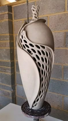 a white sculpture sitting on top of a table next to a brick wall and floor