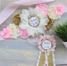 pink and white flowers are on display next to a potted plant with ribbons around it