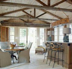 an open living room and dining area with wood beams on the ceiling, white carpeted flooring and large windows