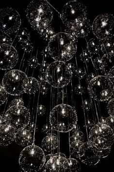 a chandelier made out of glass balls hanging from it's ceiling in the dark