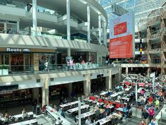 the inside of a shopping mall filled with lots of tables and people walking around it