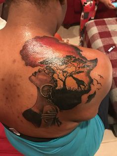 the back of a woman's shoulder with an elephant and tree tattoo on it