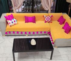 a yellow couch with pink and purple pillows