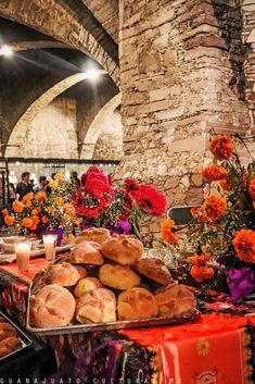 there are many different types of breads on the table in front of flowers and candles