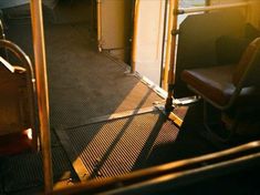 the sun is shining down on an empty bus seat and its door opened to let in some light