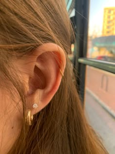 a close up of a person's ear wearing gold earrings