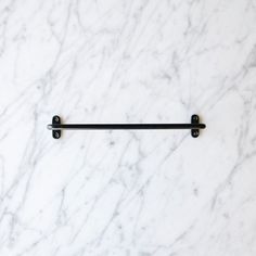 a white marble counter top with two black metal bars on it's end and one is