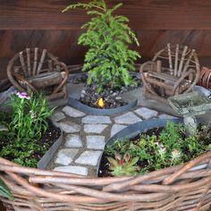 a wicker basket filled with potted plants on top of a stone floor next to a wooden fence