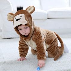 a baby in a monkey costume playing with a toothbrush on the floor next to a white couch