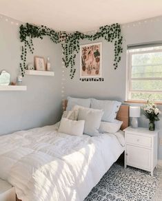 a white bed sitting in a bedroom next to a window with plants growing on it