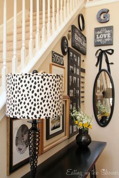 a black table with a lamp and pictures on the wall next to a stair case