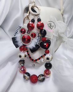 a red and black beaded necklace on a white bag with other items around it