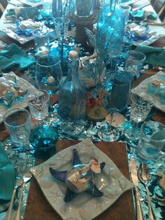 the table is set with blue glass dishes and silverware