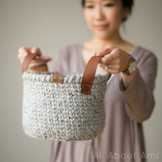 a woman holding a crocheted basket in her hands