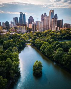 an aerial view of the city skyline and river with trees on both sides, surrounded by tall buildings