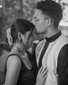 a man and woman standing next to each other in black and white with lights behind them