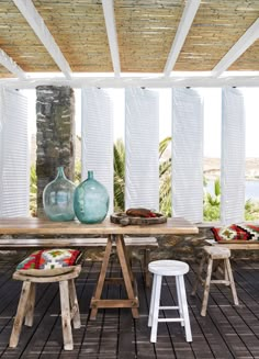 a wooden table with two vases sitting on top of it next to stools