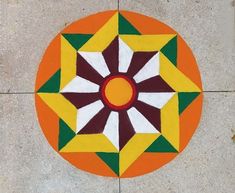 an orange, yellow and green circular design on the ground with white dots around it