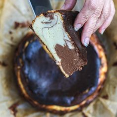 a person holding a piece of cake with chocolate frosting on it and a knife in the middle