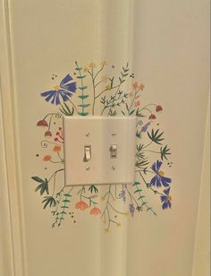 a white light switch sitting on top of a wall next to a flowery design