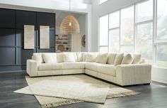 a living room with a large white sectional couch and rug in front of the windows