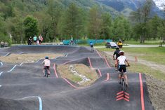 several people riding bikes on a bike track in the park with mountains in the background