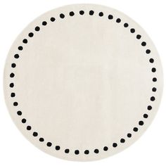 a white rug with black dots on the middle and bottom of it, in an oval shape