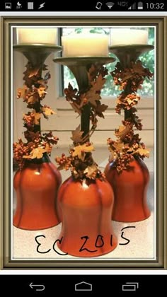 three orange vases with leaves and candles in them