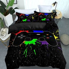 a bed with a black comforter covered in colorful paint splattered video game controllers