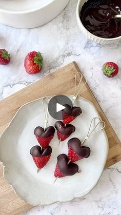 strawberries in the shape of hearts on a plate with chocolate sauce and strawberries